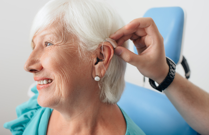 A woman is fitted for a hearing aid.